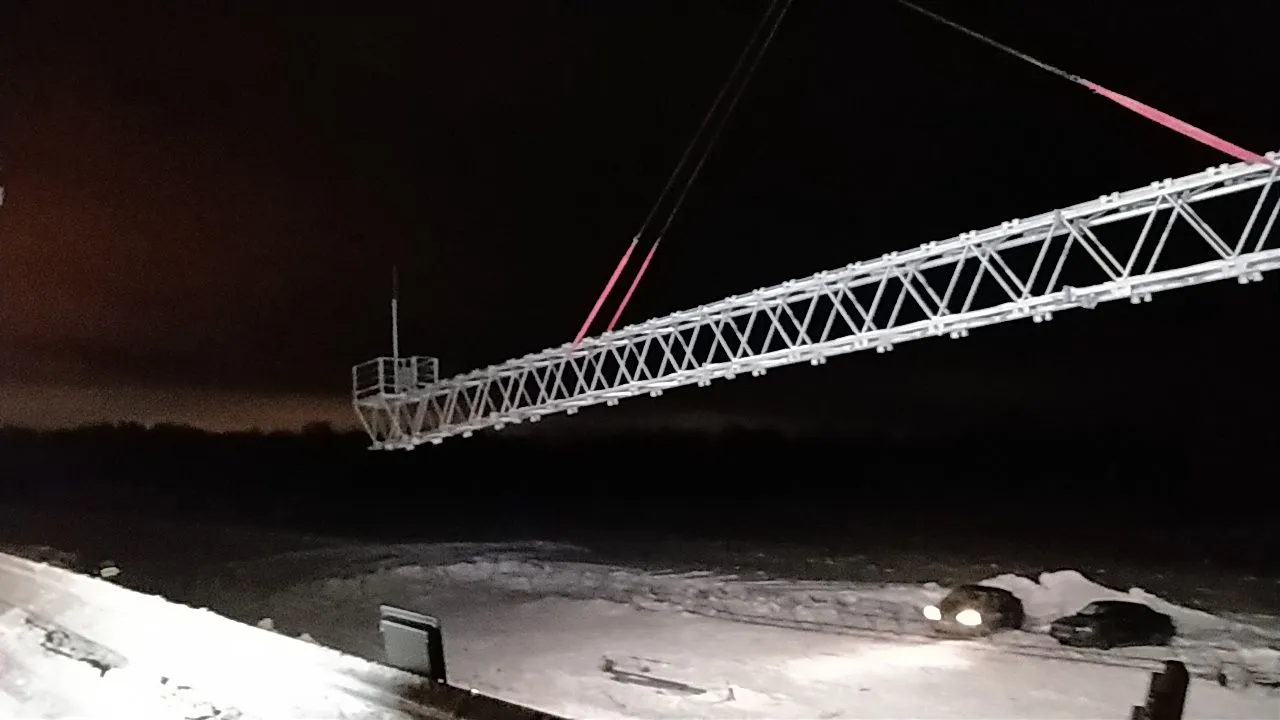 Ферма ССК поднимается крановой стрелой ночью